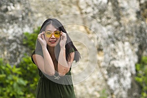 Outdoors lifestyle portrait of young happy and beautiful Asian Korean woman in green Summer dress  in hipster sunglasses playful