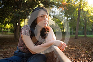 Outdoors lifestyle portrait of young happy and beautiful Asian Korean woman relaxed and thoughtful at sitting pensive on city park