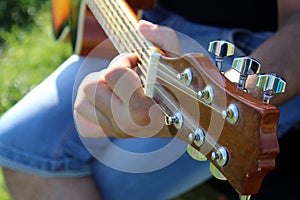 Outdoors, a man plays the guitar on a sunny day