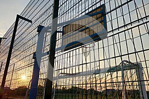 Outdoors mini football and basketball court with ball gate and basket surrounded with high protective fence