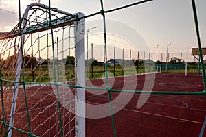 Outdoors mini football and basketball court with ball gate and basket surrounded with high protective fence