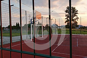 Outdoors mini football and basketball court with ball gate and basket surrounded with high protective fence