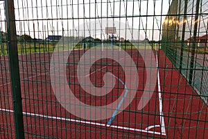Outdoors mini football and basketball court with ball gate and basket surrounded with high protective fence
