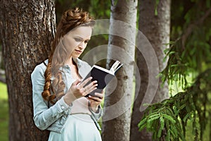 Outdoors portrait of a beautiful girl reading book