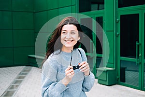 Outdoors portrait of beautiful young brunette girl smiling. Teenager hipster girl with sunglasses wearing trendy outfit posing in