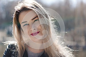 Outdoors portrait of beautiful young brunette girl. Woman smiling happy on sunny summer or spring day outside on city background.