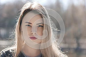 Outdoors portrait of beautiful young brunette girl. Woman smiling happy on sunny summer or spring day outside on city background.