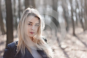 Outdoors portrait of beautiful young brunette girl. Woman smiling happy on sunny summer or spring day outside on city background.