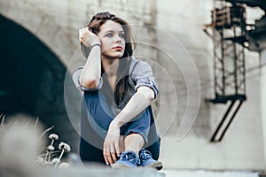 Outdoors portrait of beautiful young sad teen girl sitting on stairs.