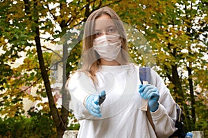 Outdoors portrait of beautiful young woman wearing cotton white mask and medicalgloves greeting and say hello, Nature and trees in