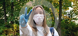 Outdoors portrait of beautiful young woman wearing cotton white mask and medicalgloves greeting and say hello, Nature and trees in