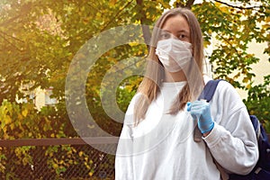 Outdoors portrait of beautiful young woman wearing cotton white mask and medicalgloves greeting and say hello, Nature and trees in