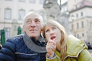 Outdoors portrait of elderly man and his young blonde wife spending time together in the ancient city during early