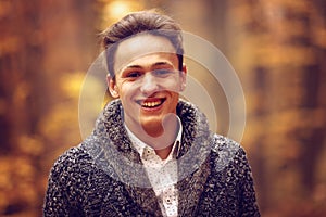 Outdoors portrait of happy young man standing in autumn park at