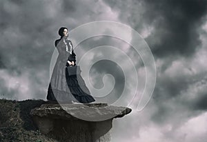 Outdoors portrait of a victorian lady in black standing on the cliff