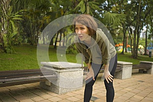 Outdoors portrait of young attractive tired and breathless jogger woman in breathing exhausted after running workout at beautiful photo