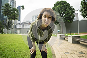 Outdoors portrait of young attractive tired and breathless jogger woman in breathing exhausted after running workout at beautiful photo