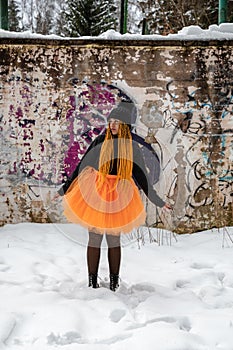 Young beautiful girl  with an orange box braids hairstyle and in a bright orange skirt against an abandoned