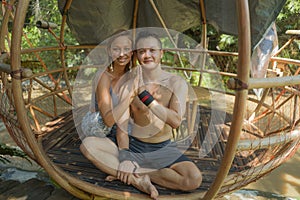 Outdoors portrait of young beautiful and happy couple practicing yoga workout together at tropical forest gazebo smiling cheerful