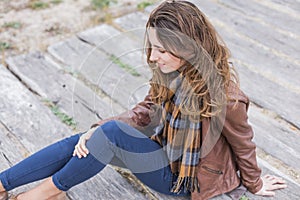 Outdoors portrait of a young woman with brown jacket, jeans and photo