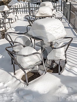 Outdoors restaurant chairs and tables covered with thick snow cover