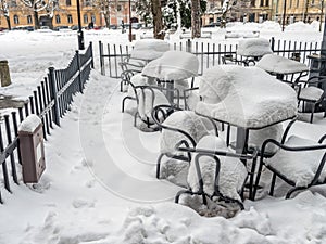 Outdoors restaurant chairs and tables covered with thick snow cover