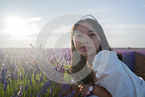 Outdoors romantic portrait of young happy and attractive woman in white summer dress enjoying carefree at beautiful lavender