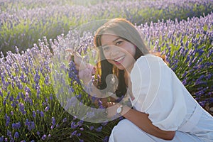 Outdoors romantic portrait of young happy and attractive woman in white summer dress enjoying carefree at beautiful lavender