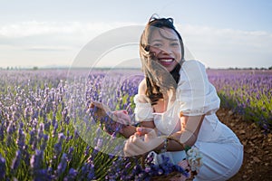 Outdoors romantic portrait of young happy and attractive woman in white summer dress enjoying carefree at beautiful lavender