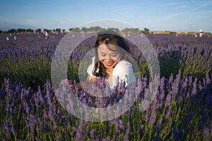 Outdoors romantic portrait of young happy and attractive woman in white summer dress enjoying carefree at beautiful lavender