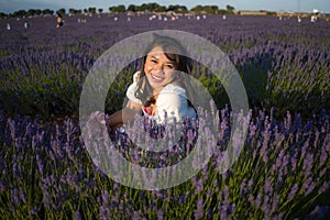 Outdoors romantic portrait of young happy and attractive woman in white summer dress enjoying carefree at beautiful lavender