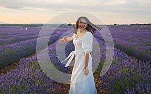 Outdoors romantic portrait of young happy and attractive woman in white summer dress enjoying carefree at beautiful lavender