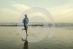 Outdoors running workout - young attractive and athletic runner man jogging on beautiful beach in Summer training happy and free