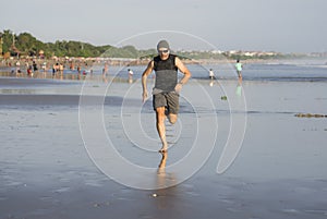 Outdoors running workout - young attractive and athletic runner man jogging on beautiful beach in Summer training happy and free