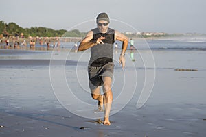 Outdoors running workout - young attractive and athletic runner man jogging on beautiful beach in Summer training happy and free
