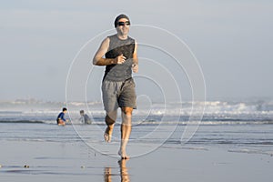 Outdoors running workout - young attractive and athletic runner man jogging on beautiful beach in Summer training happy and free