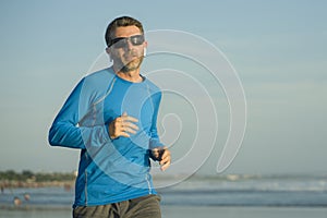 Outdoors running workout - young attractive and athletic runner man jogging on beautiful beach in Summer training happy and free