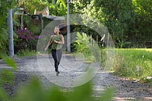Outdoors running workout - young happy and dedicated Asian Chinese woman jogging at beautiful city park or countryside trail on