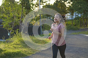 Outdoors running workout - young happy and dedicated Asian korean woman jogging at beautiful city park or countryside trail on