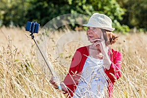 Outdoors selfie for beautiful 50s woman in high dry grass