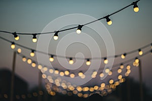 Outdoors wedding decoration with light bulbs at sunset