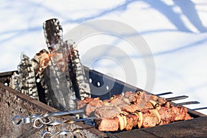 Outdoors winter barbecue party with a person wearing knitted woollen gloves cooking meat