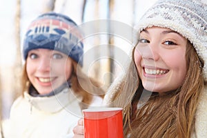 Outdoors on a winter day. Girls drink tea.