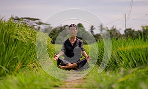 Outdoors yoga and meditation at rice field - attractive and happy middle aged Asian Japanese woman enjoying yoga and relaxation in