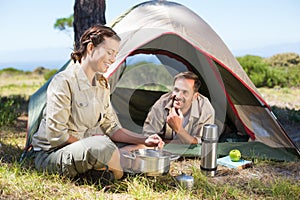 Outdoorsy couple cooking on camping stove outside tent