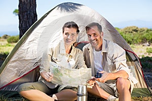 Outdoorsy couple looking at the map outside tent