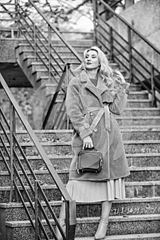 Outerwear of modern warm and stylish eco fur. Girl warm coat stand urban stairs background. Create fall outfit to feel