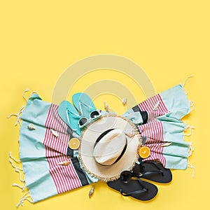 Outfit for beach tropical vacations, straw sun hat, towel, sun glasses on yellow. Summer concept. Top view