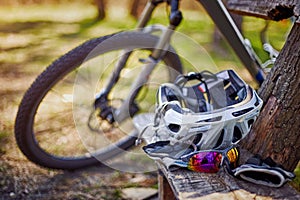 Outfit for bicycles, helmet, gloves on the bench on a sunny day.