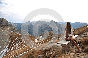 Outfit of casual woman. Brunette sitting on bench enjoying nature above mountains view landscape. Travel Lifestyle adventure